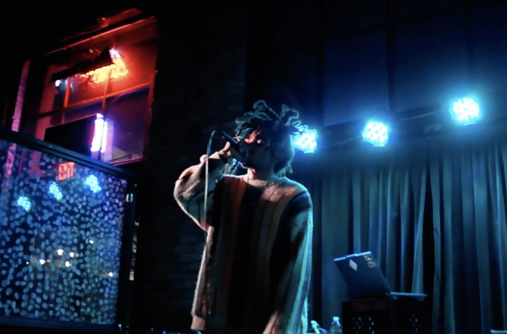 AJANIMF under blue stage lights performing tracks off of his 2025 project 'HOLD DIS' as part of the FREE ZANDER concert at Underground Music Venue in Minneapolis, MN