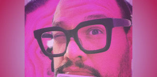 Frank Panduh pictured with thick-framed glasses holding a white music production pad with a gradient pink backdrop; feature photo for a review of his single "Cabbage"