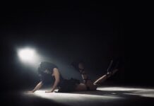 Viris Valentine Creates a “Dystopia” You Don’t Want To Leave Viris Valentine in a black dress laying on a hard floor propped up by her hands and kicking her legs underneath an off-center spotlight for the "Dystopia" cover art